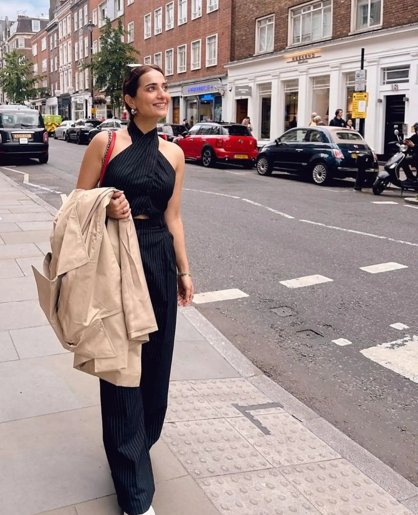 Black halter-neck dress with ribbed pants and beige jacket.