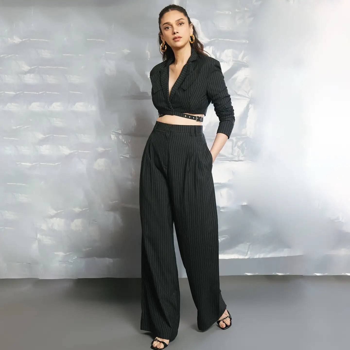 Black pleated wide-leg pants with a gold belt and open front top.