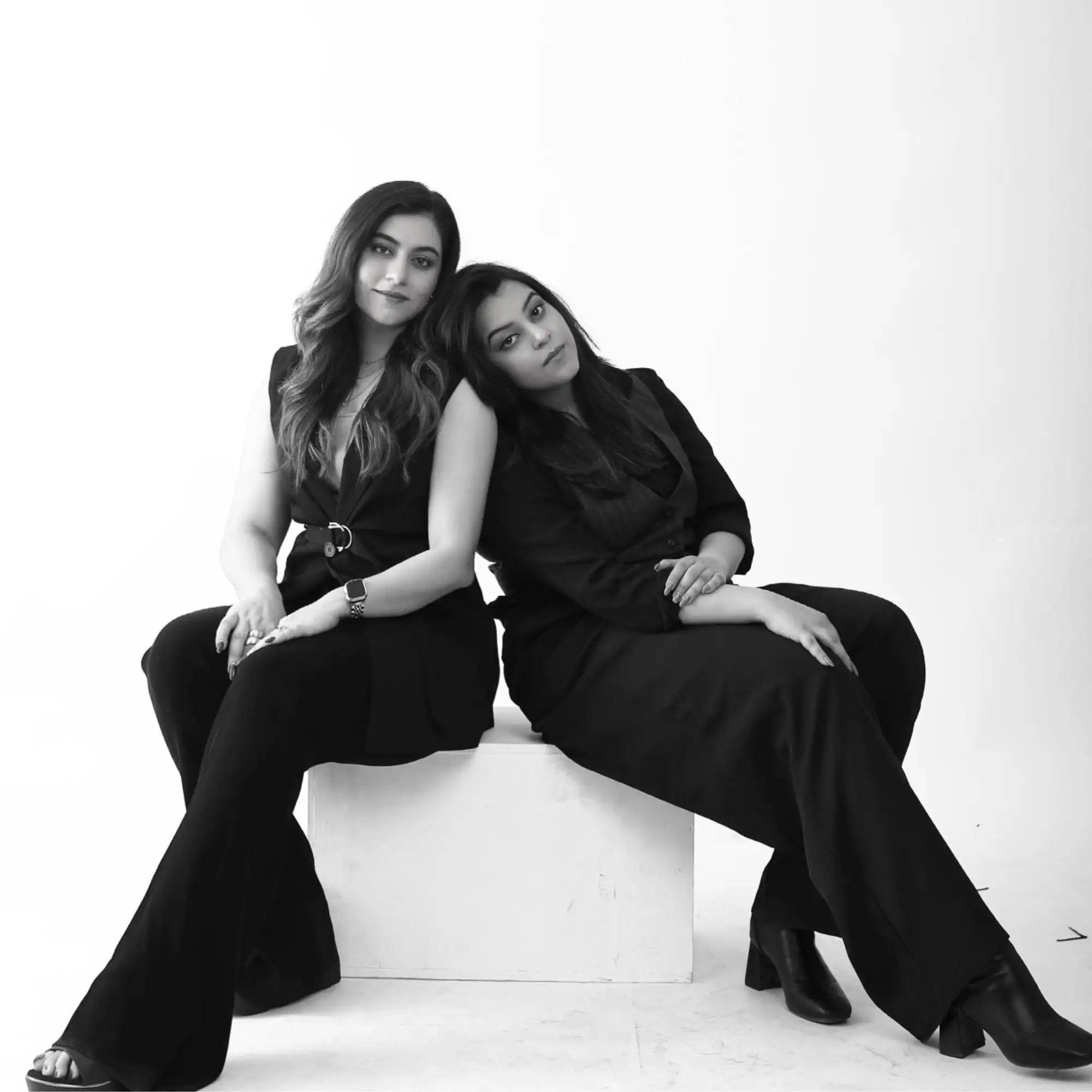 Black and white photograph of two women sitting on a cube.