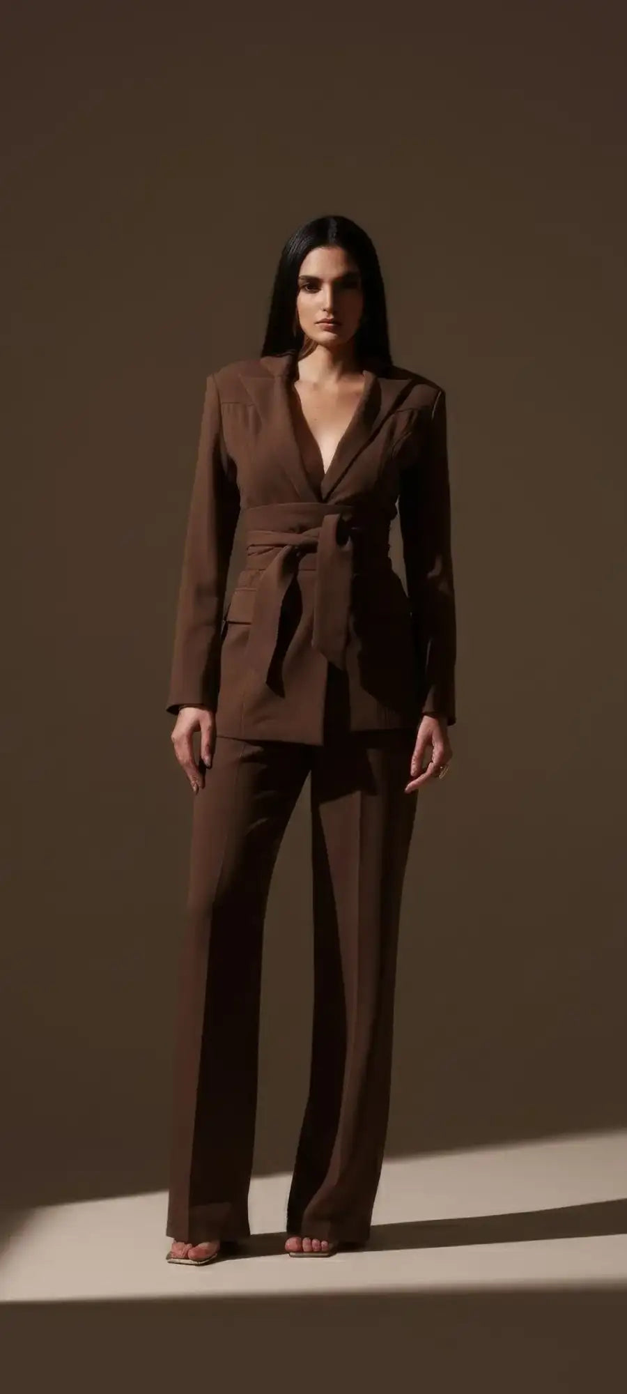 Brown tailored blazer with a belted waist and structured shoulders.