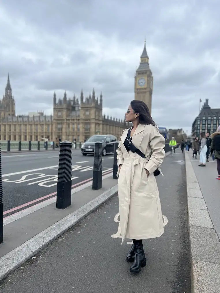 Cream-colored trench coat with black accents and a classic design.
