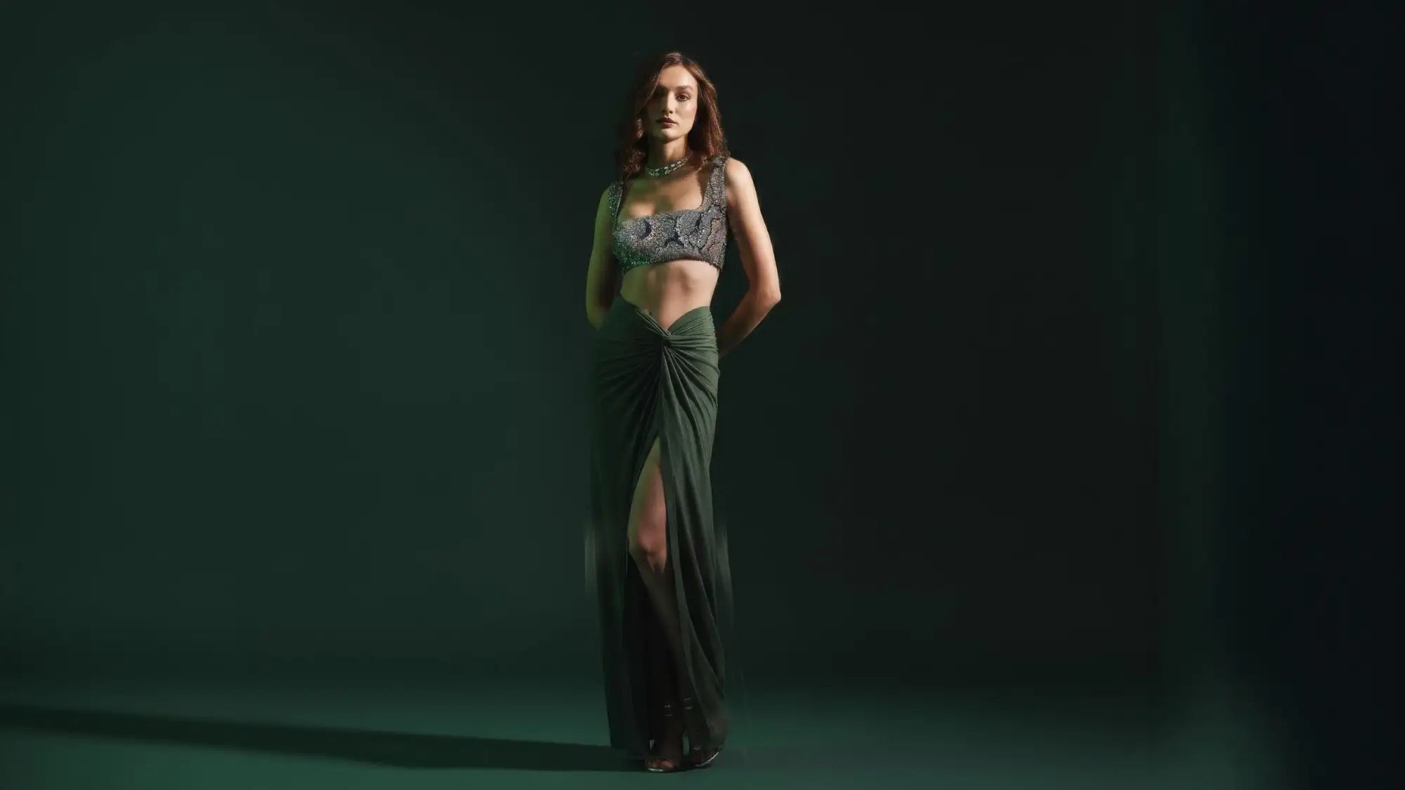 Elegant emerald green draped gown with a beaded, cropped top.