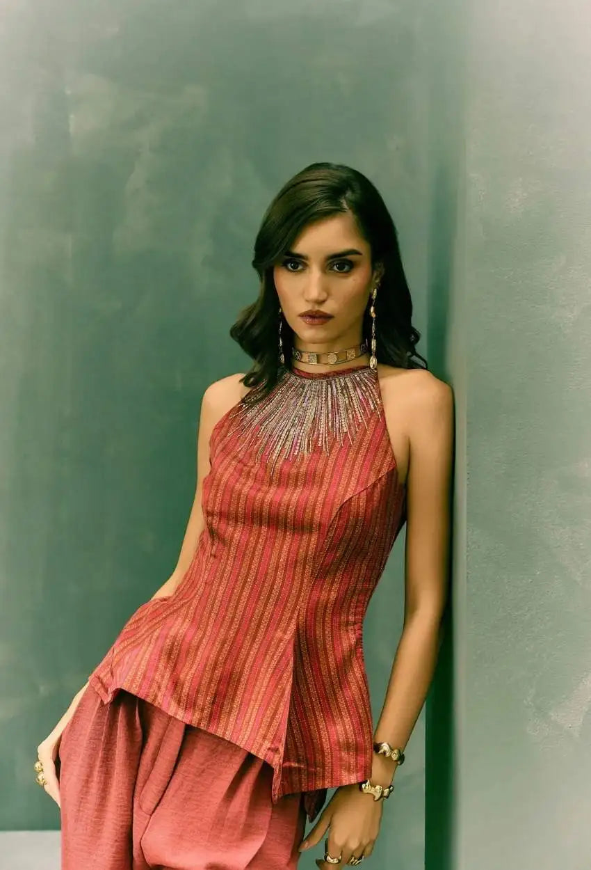A sleeveless, high-necked top in a rich terracotta hue with vertical ribbed texture and metallic thread detailing at the neckline.