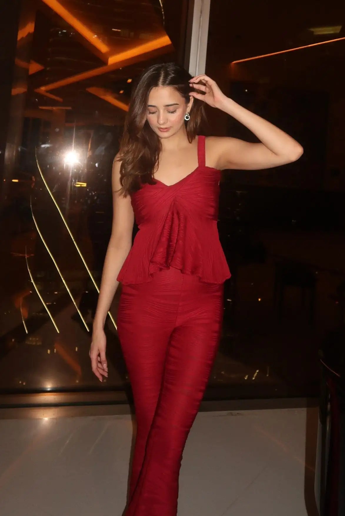A vibrant red peplum top with a ruched front and thin straps, paired with matching high-waisted trousers.