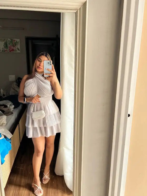 White pleated mini dress with lace detailing and a high neckline.