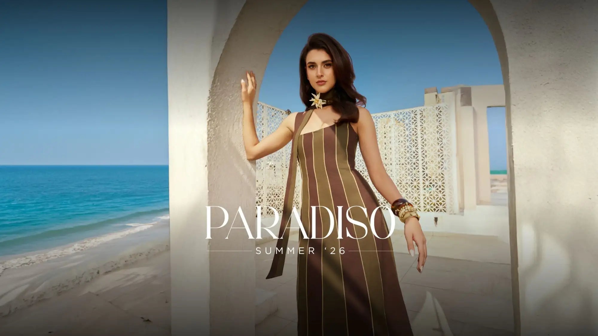 A woman wears a long, sleeveless dress with vertical brown and beige stripes.